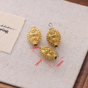 Macro detail of gold vintage oval beads with 1.5mm hole showing embossed floral patterns