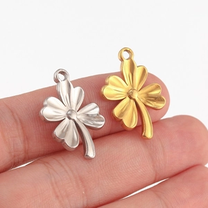 Pendentifs trèfle en acier poli or et argent tenus pour montrer les détails