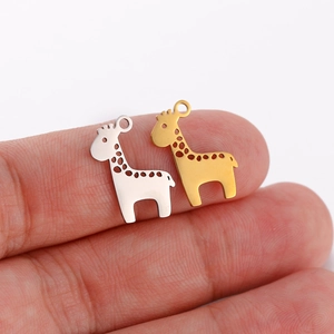 Detailed view of tiny hollow-out giraffe pendants in gold and silver held on fingertips