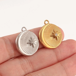 Gros plan de pendentifs lune or et argent avec cristaux centraux sur le doigt