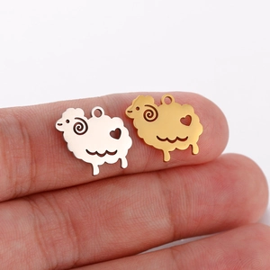 Detailed close-up of gold and silver sheep pendants on fingertips for scale