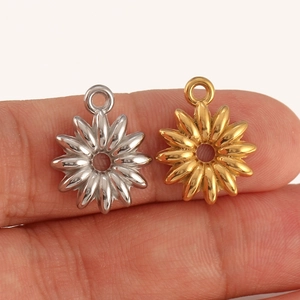 Detail of silver and gold stainless steel flower charms held on finger showing small size