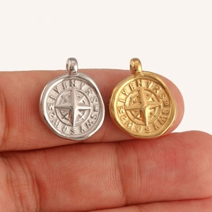 Macro shot of gold and silver compass pendants showing the detailed starburst engraving