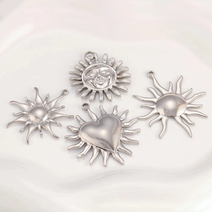 Detailed macro view of four polished stainless steel sun and heart DIY jewelry pendants