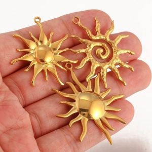 Three gold stainless steel sun pendants with different radiant ray designs held in hand