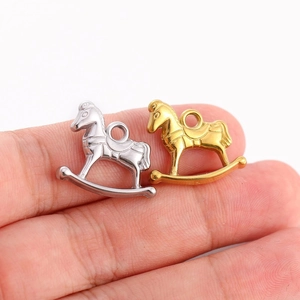 Gros plan de petits pendentifs cheval à bascule en acier inoxydable doré et argenté