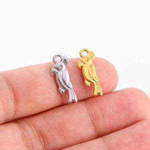 Pendentifs perroquet en or et argent polis tenus sur les doigts pour l'échelle