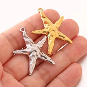 Starfish charms in gold and silver finish on hand showing product size and details