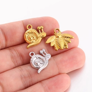 Pendentifs escargot et abeille en acier inoxydable doré et argenté tenus en main