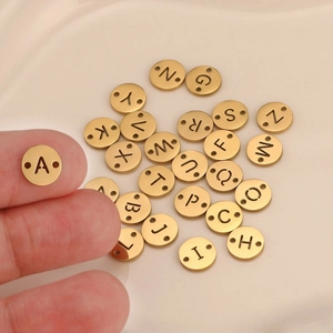 Detail of 8mm golden stainless steel DIY alphabet pendants with double holes for bracelets