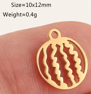 Macro view of a 10x12mm hollow gold fruit pendant charm held on a fingertip
