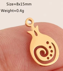 Detailed macro view of a gold-plated pomegranate fruit pendant being held by fingers