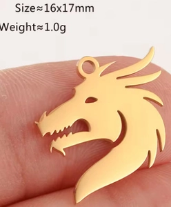 Macro shot of a 16x17mm gold stainless steel dragon pendant held on a fingertip