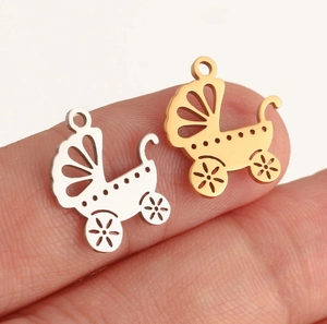 Macro shot of mini gold and silver baby stroller charms in polished stainless steel
