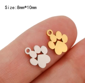 Nahaufnahme winziger goldener und silberner Pfotenanhänger mit Herz für DIY-Schmuck