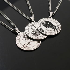 Detailed macro shot of zodiac coin pendants showing Leo and Taurus symbols in silver steel