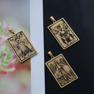 Détail de trois pendentifs tarot dorés vintage avec les motifs La Tour, Diable et Tempérance