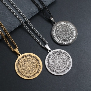 Trois pendentifs runes Viking Odin en or, argent et noir sur une surface en pierre