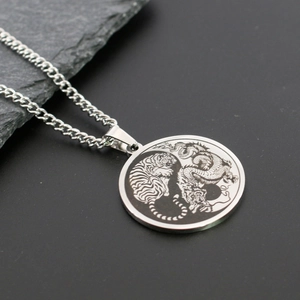 Detailansicht von Edelstahl Yin-Yang-Drachen- und Tigeranhänger auf Steinoberfläche
