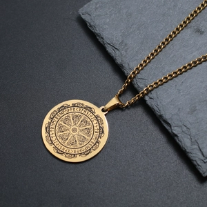 Détail du pendentif boussole viking dorée avec runes nordiques sur pierre brute