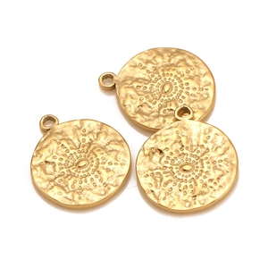 Detailed macro view of three gold sunburst engraved round charms for DIY jewelry making