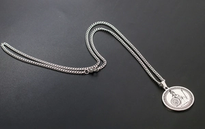 Macro shot of silver Athena pendant with Greek key border and intricate embossed details