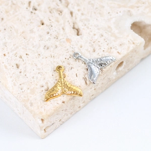 Detailed macro view of gold and silver mermaid tail pendants with hammered texture finish