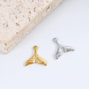Macro detail of gold and silver mermaid tail pendants with hammered metal texture