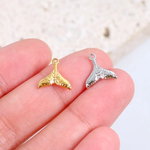 Detailed view of gold and silver stainless steel mermaid tail charms with textured finish