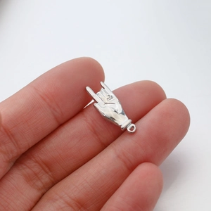 Vue détaillée d'un pendentif en argent poli en forme de geste de main tenu par les doigts