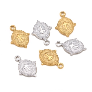 Detailed macro of oval cross pendants in gold and silver finish with embossed sunburst texture