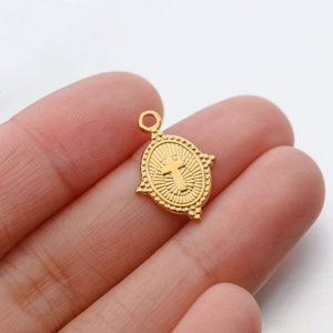 Detailed close-up of a gold-plated oval cross pendant with vintage engraved sunburst pattern