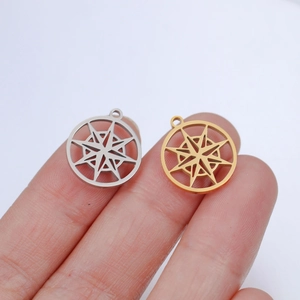 Macro shot of gold and silver stainless steel compass pendants on a fingertip