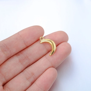 Polished golden crescent moon pendant charm in stainless steel held by hand for scale
