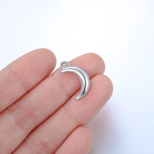 Polished stainless steel crescent moon pendant held by fingers to show small size