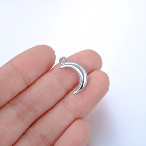 Polished stainless steel crescent moon pendant held by hand on white background