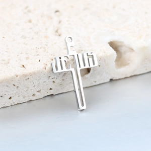 Macro shot of silver stainless steel cross pendant featuring hollowed JESUS lettering detail