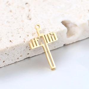 Polished gold hollow cross pendant with Hebrew lettering on a natural stone surface