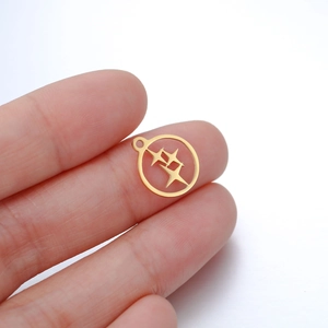 Détail d'un petit pendentif étoile dorée tenu par les doigts pour comparer la taille