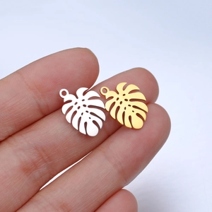 Macro shot of gold and silver monstera leaf pendants with polished hollow-out details