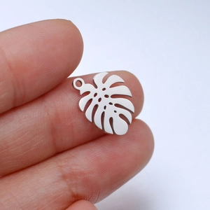 Detailed close-up of a hollow monstera leaf pendant held by hand for scale and size