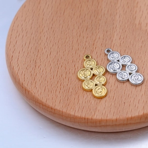 Detailed macro of gold and silver stainless steel coin cluster charms on a wood base