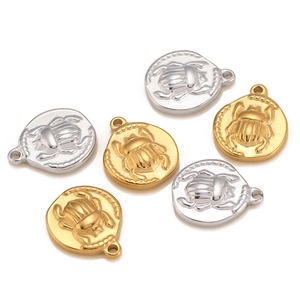 Macro view of gold and silver beetle charms with embossed scarab detail for DIY jewelry