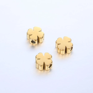 Close-up of three golden clover-shaped stainless steel beads with a mirror polish finish