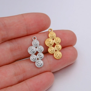 Detailed view of silver and gold geometric round pendants held by hand for DIY jewelry