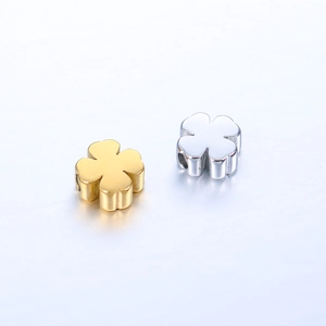 Close-up of gold and silver clover-shaped stainless steel beads with side-drilled holes