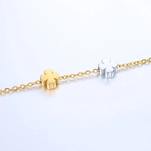 Detailed macro view of two-tone polished stainless steel four-leaf clover charms on a chain