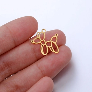 Close-up of golden balloon dog pendant held by hand for DIY jewelry making accessories