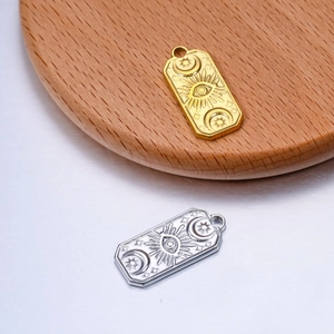 Detail of rectangular titanium steel pendants with sun, moon, and evil eye embossed motifs