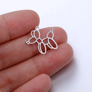Close-up of a silver stainless steel balloon dog charm held on a fingertip for DIY jewelry